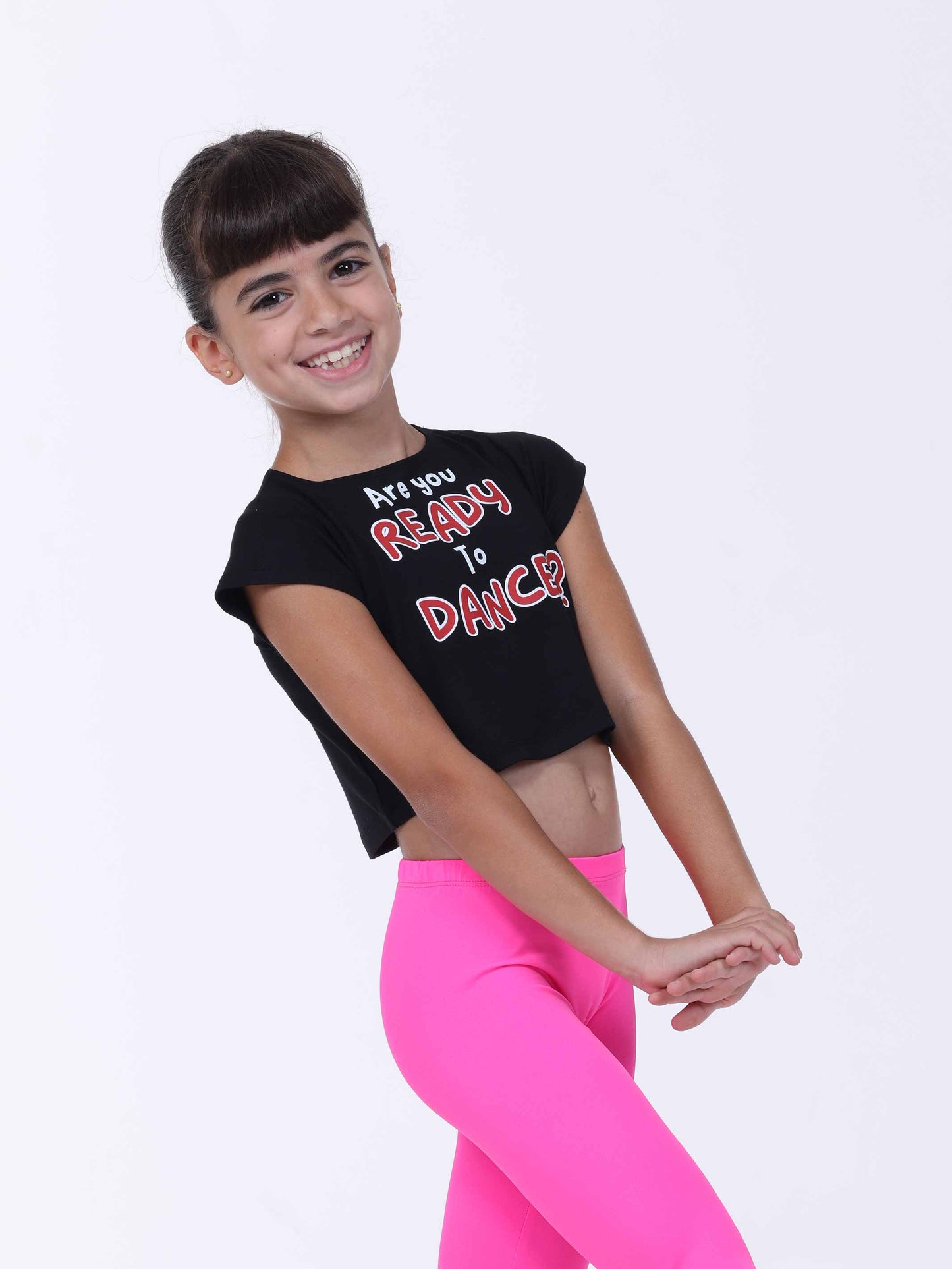 Young girl wearing a black crop top with 'Are you ready to dance?' text and pink leggings on a white background