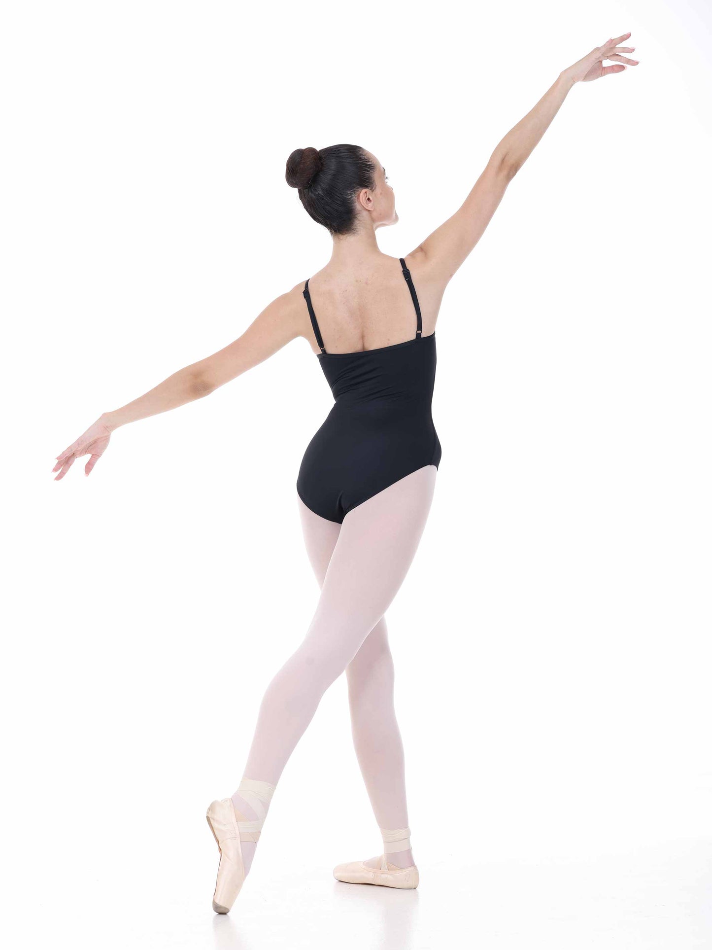 Ballerina in a black leotard and pink tights posing on a white background