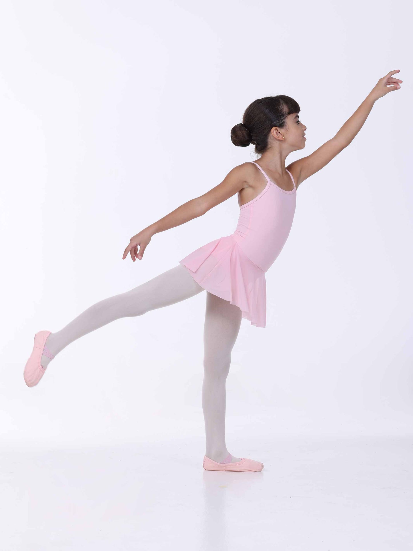 Ballerina in a pink dress and white tights posing on a white background