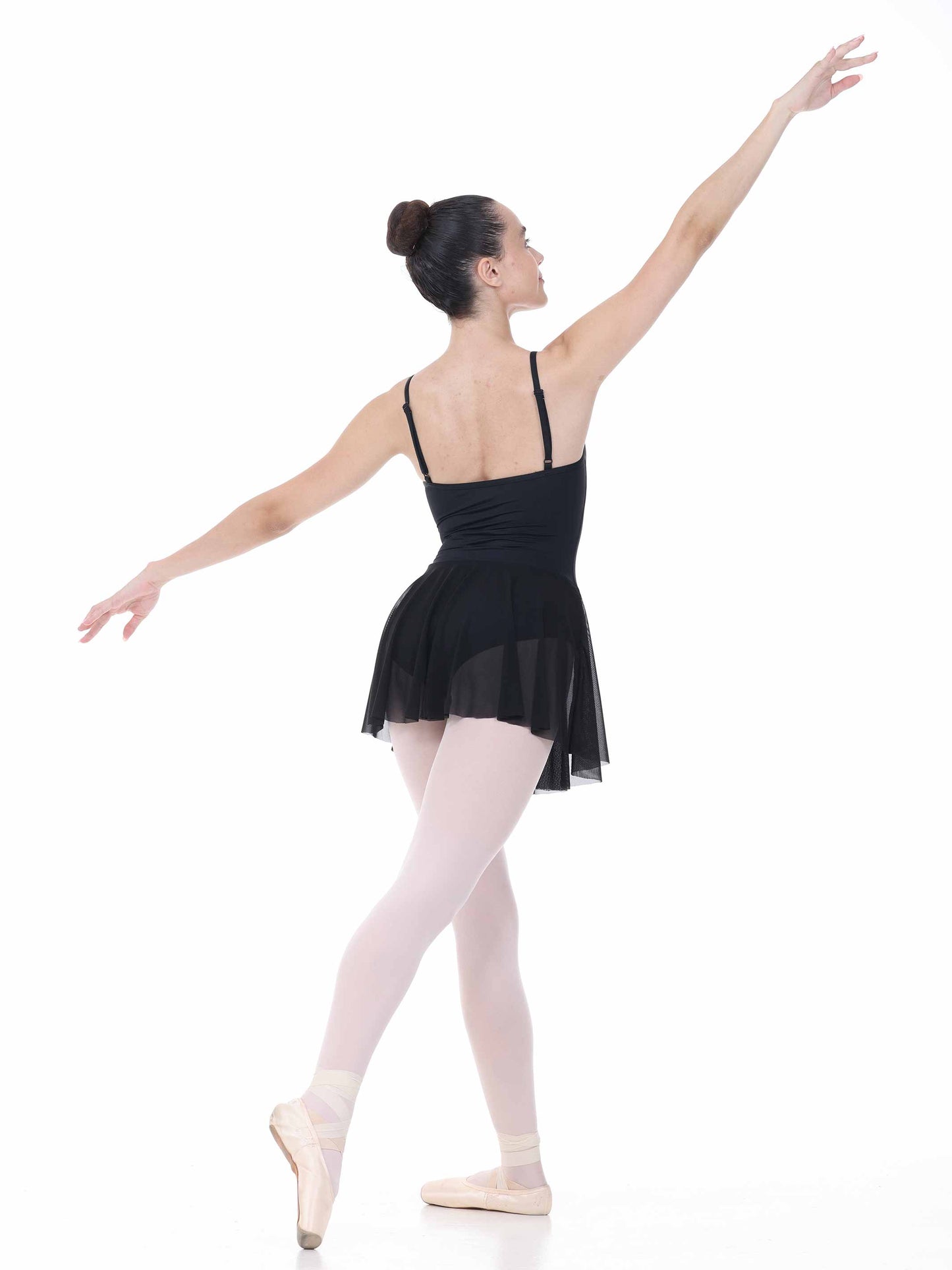 Ballerina in a black dress and pink tights posing on a white background