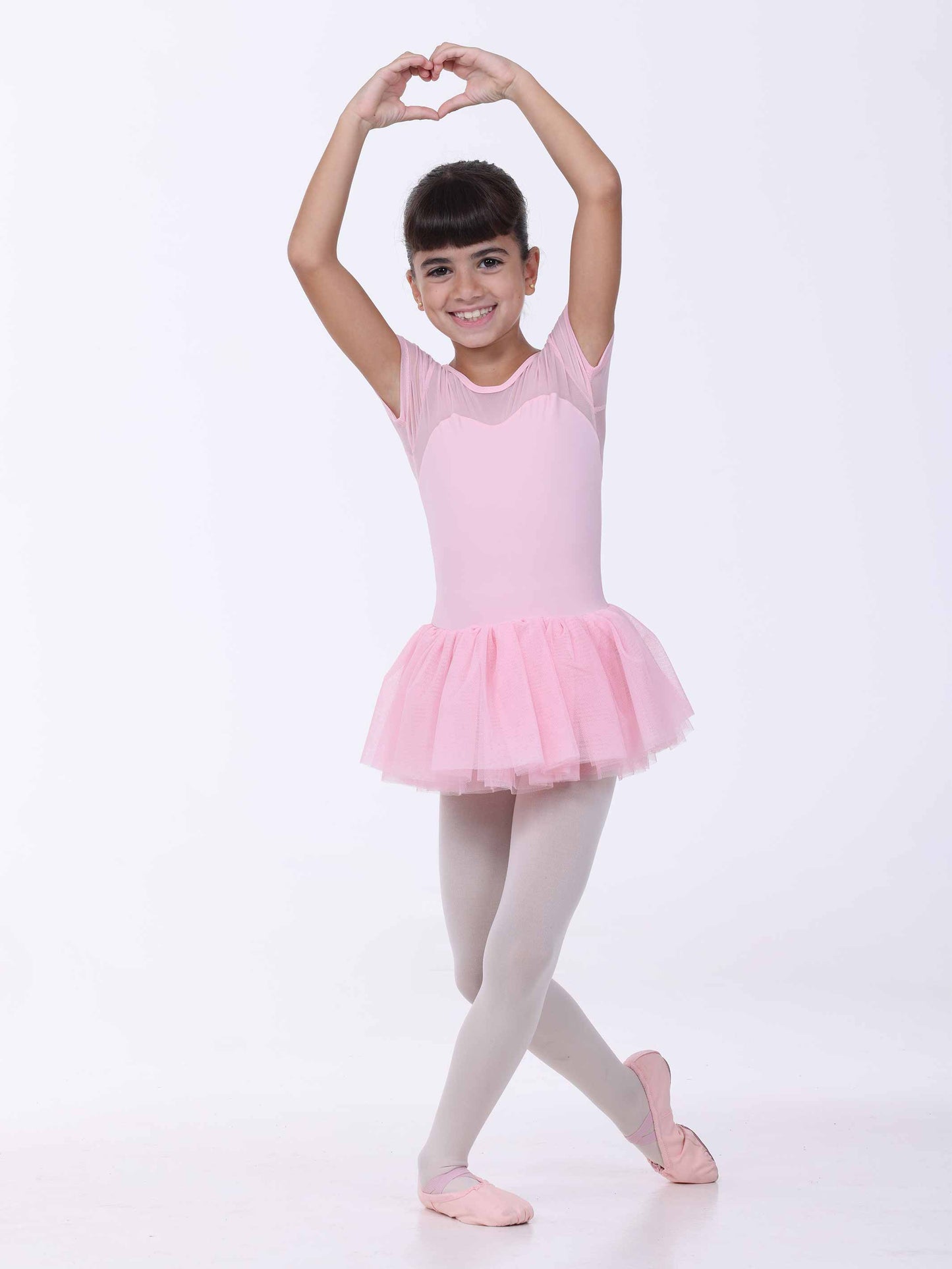 Young girl in a pink ballet outfit posing against a white background