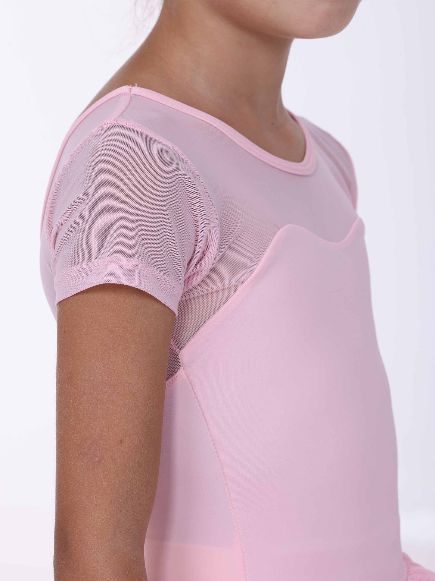 Close-up of a girl wearing a pink ballet dress with a plain background