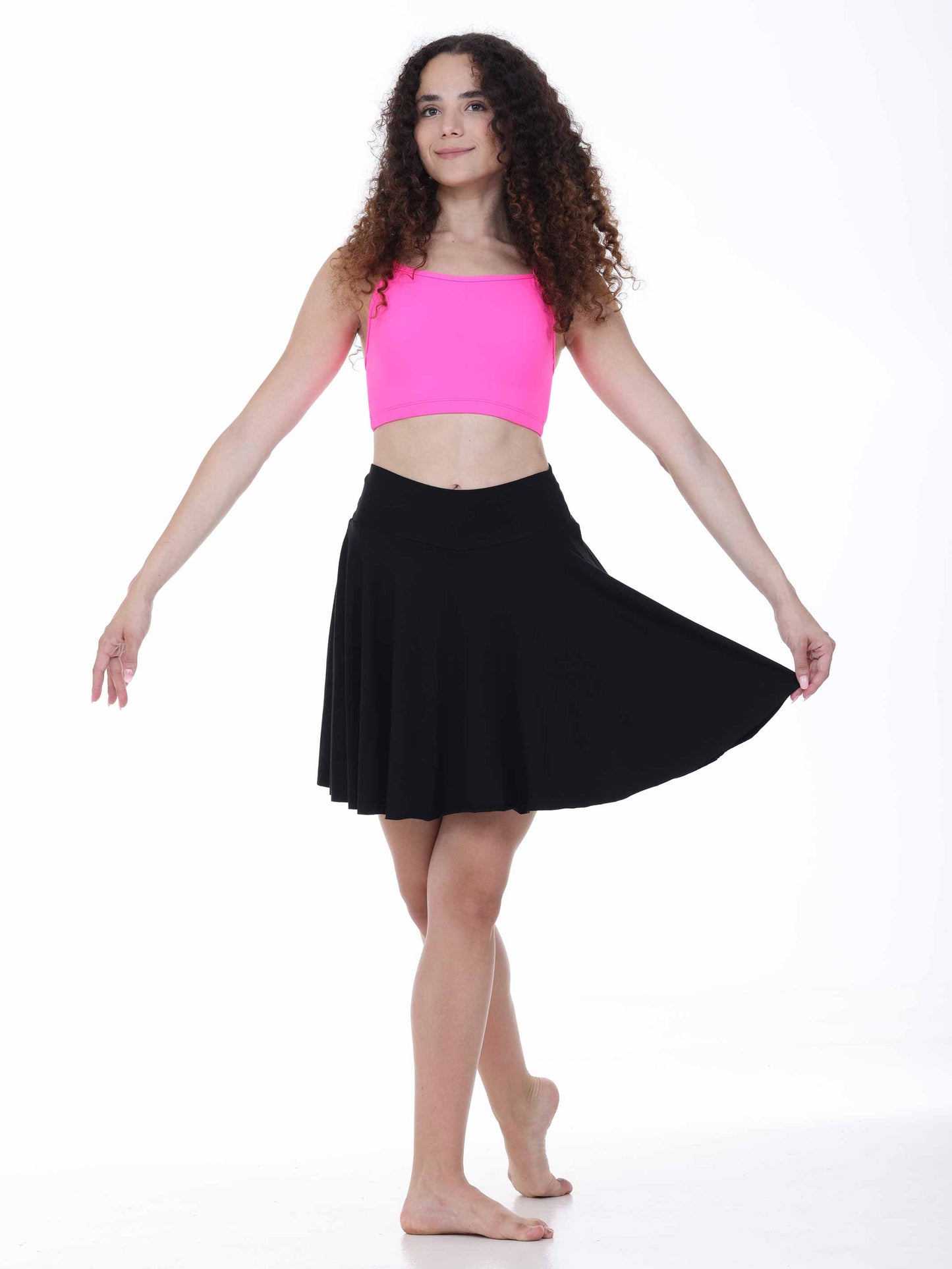 Woman wearing a pink crop top and black skirt on a white background