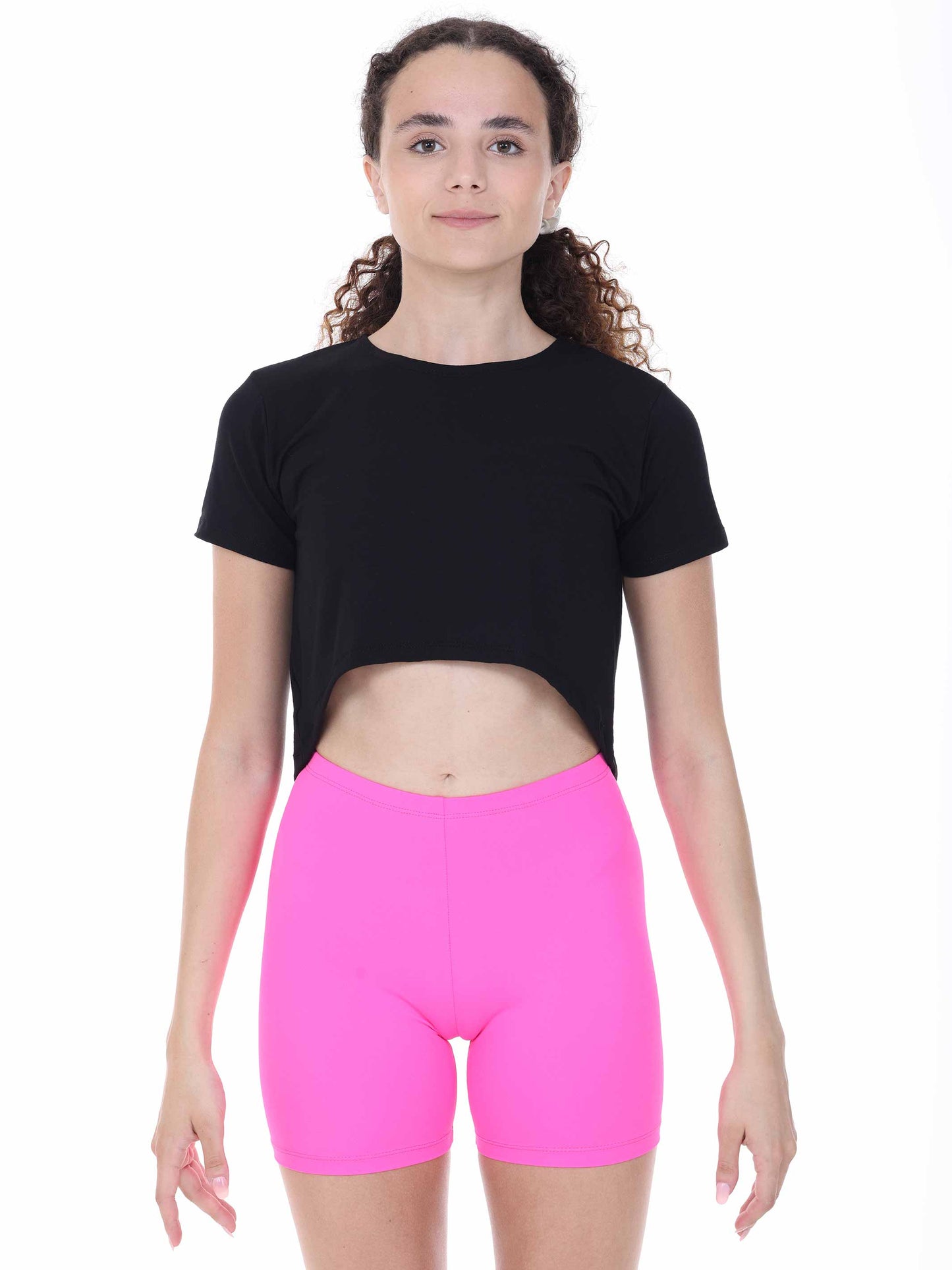 Person wearing a black dance crop top and pink shorts on a white background