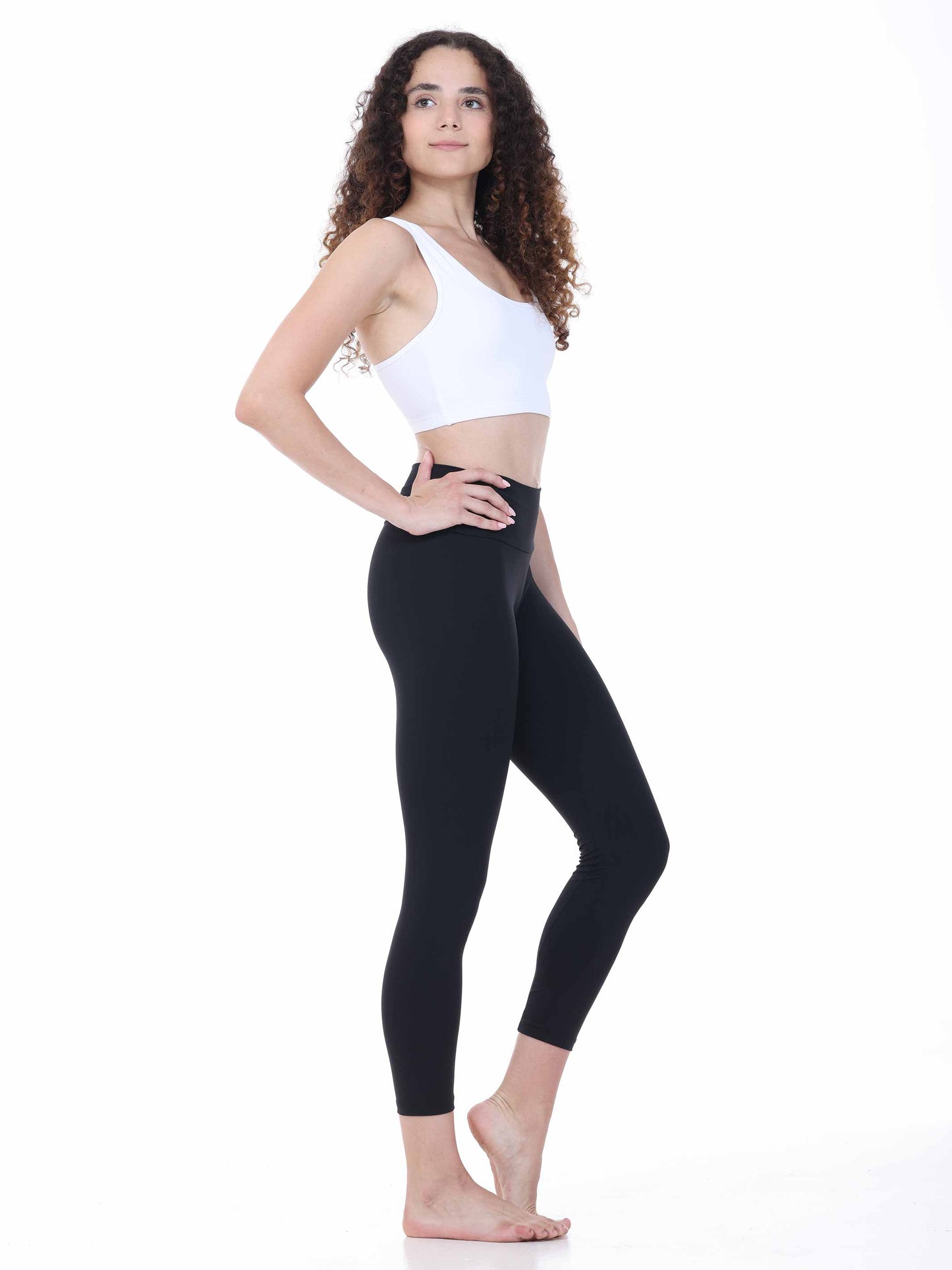 Woman wearing a white sports bra and black leggings on a white background