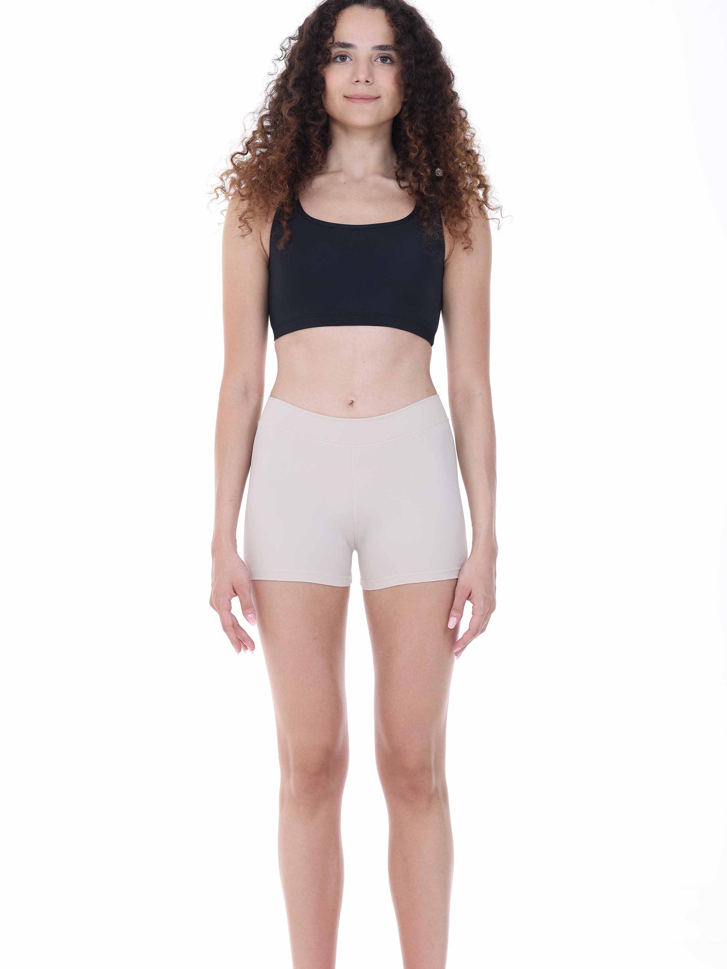Woman wearing a black crop top and beige shorts on a white background
