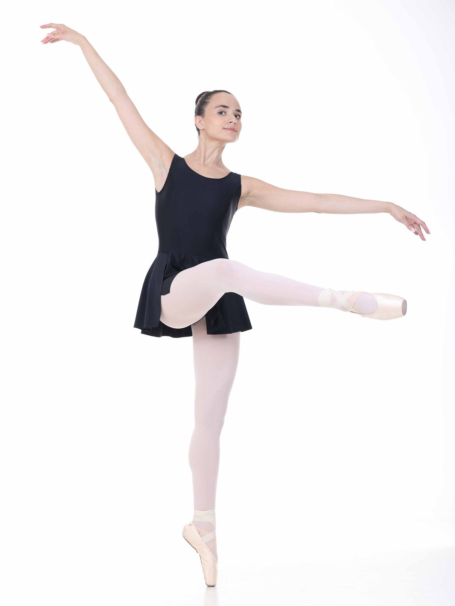 Ballerina in a black ballet dress and pink tights posing on a white background