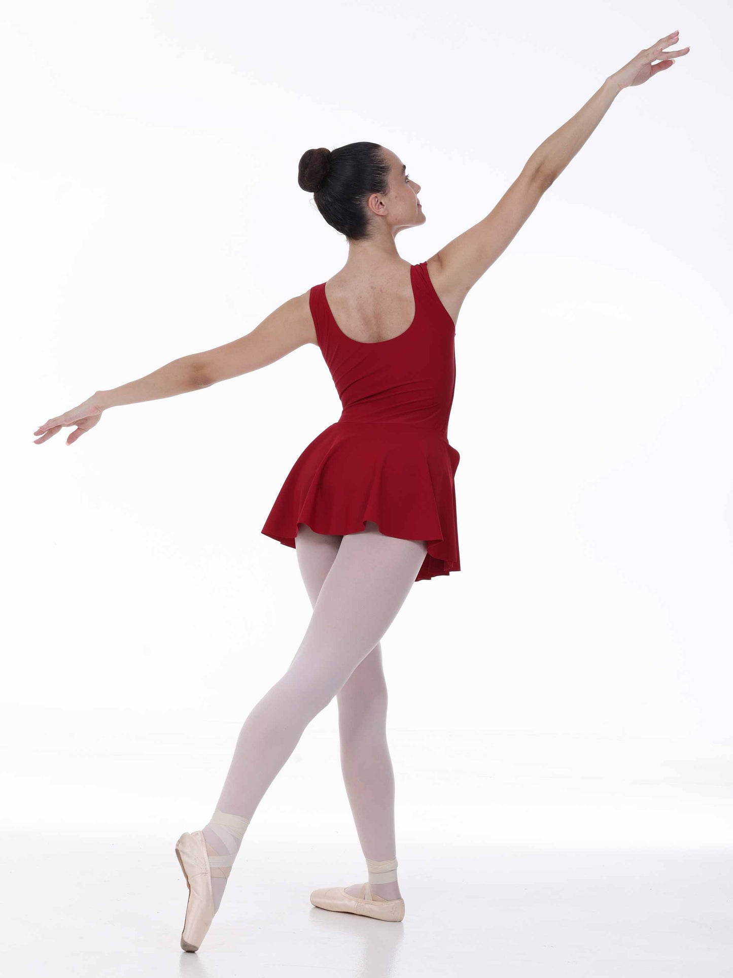 Ballerina in a red dress and white tights posing on a white background