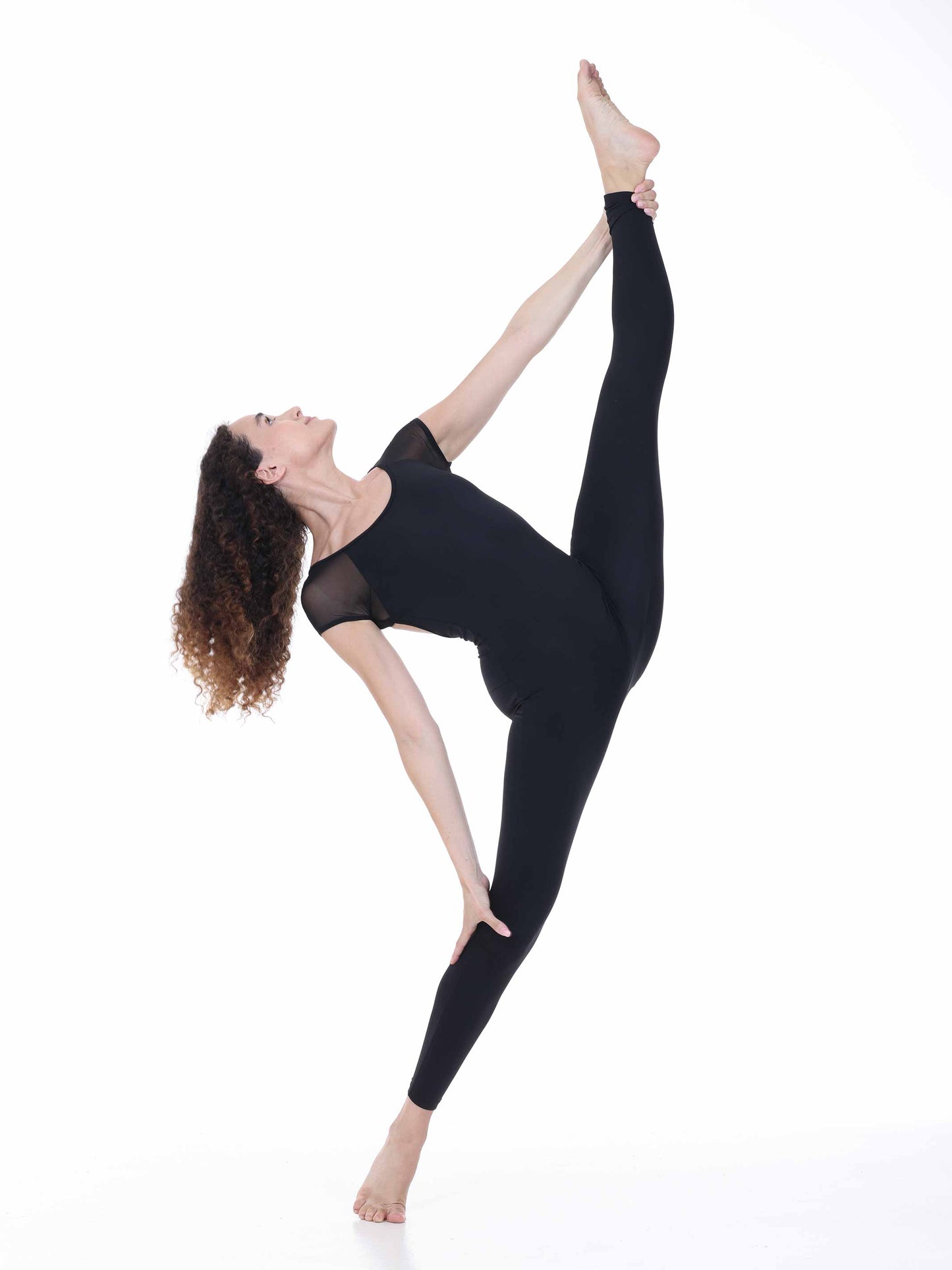 Woman in black athletic wear performing a yoga pose on a white background