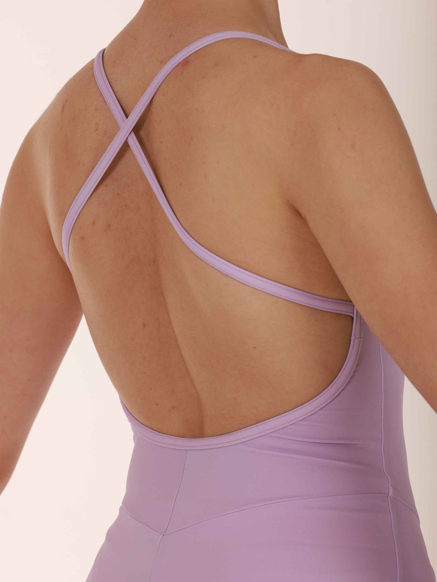 Purple strappy ballet leotard worn by a person on a plain background