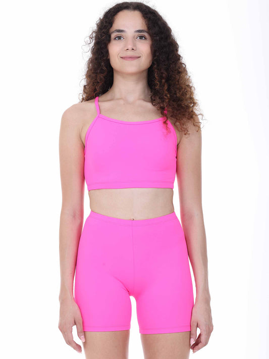 Person wearing a bright fuchsia sports bra and shorts set on a white background