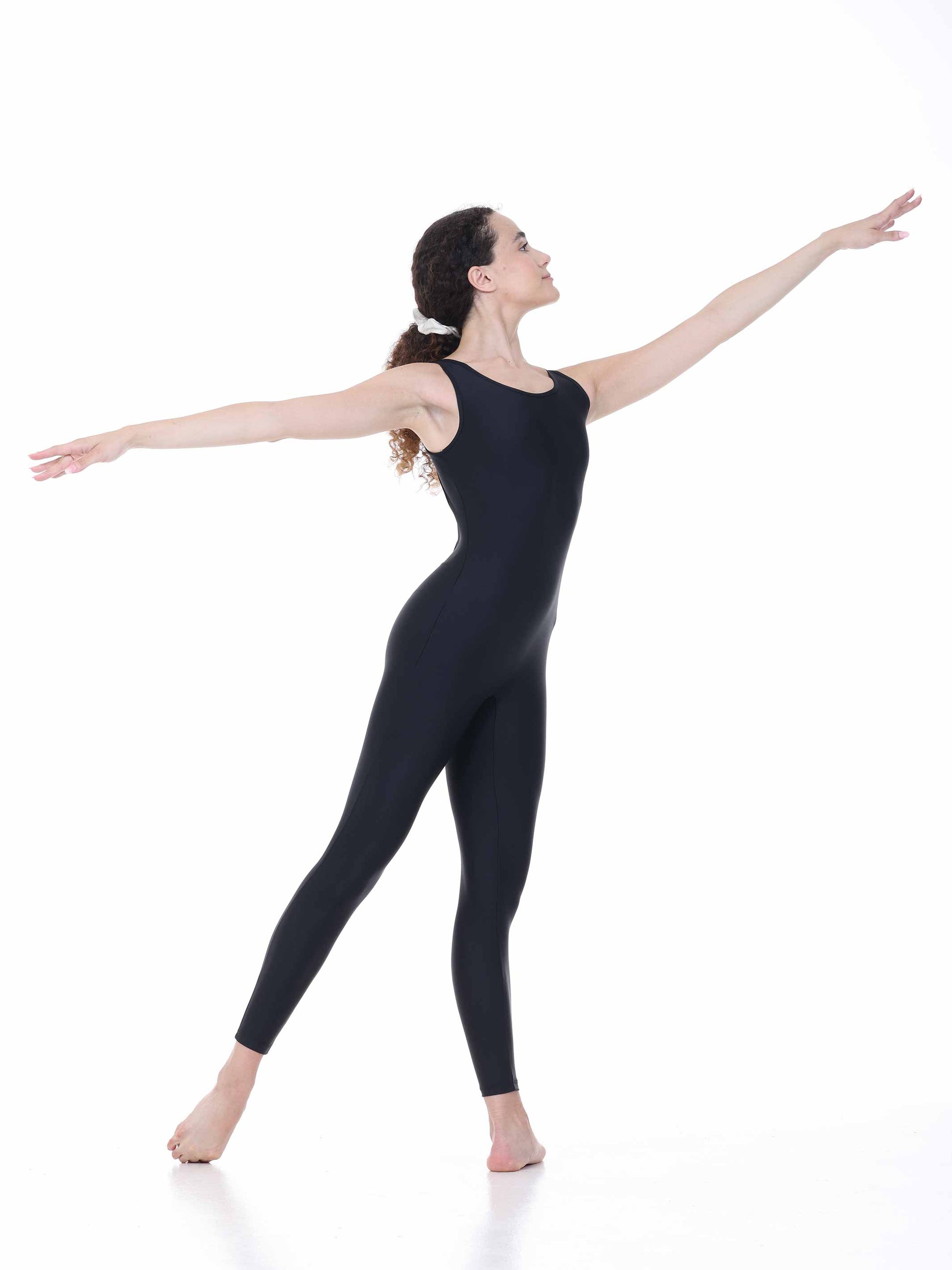 Dancer in a black unitard posing with arms outstretched on a white background