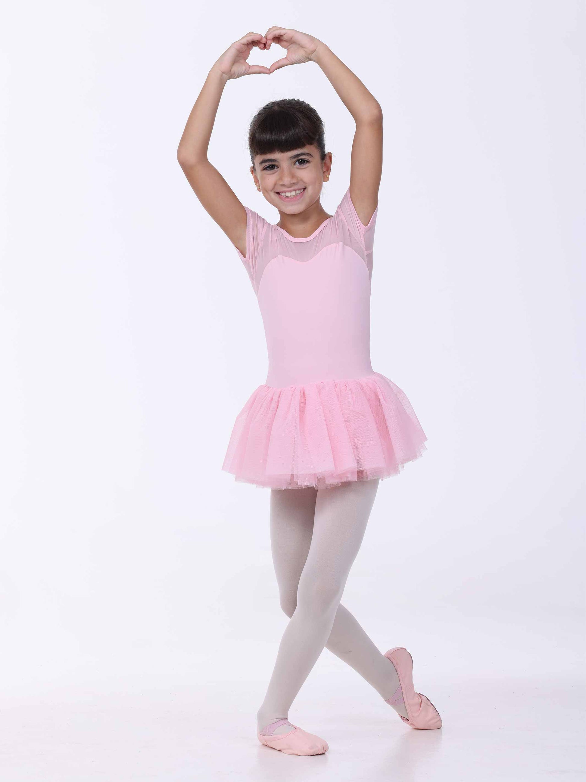 Young girl in a pink ballet outfit posing against a white background