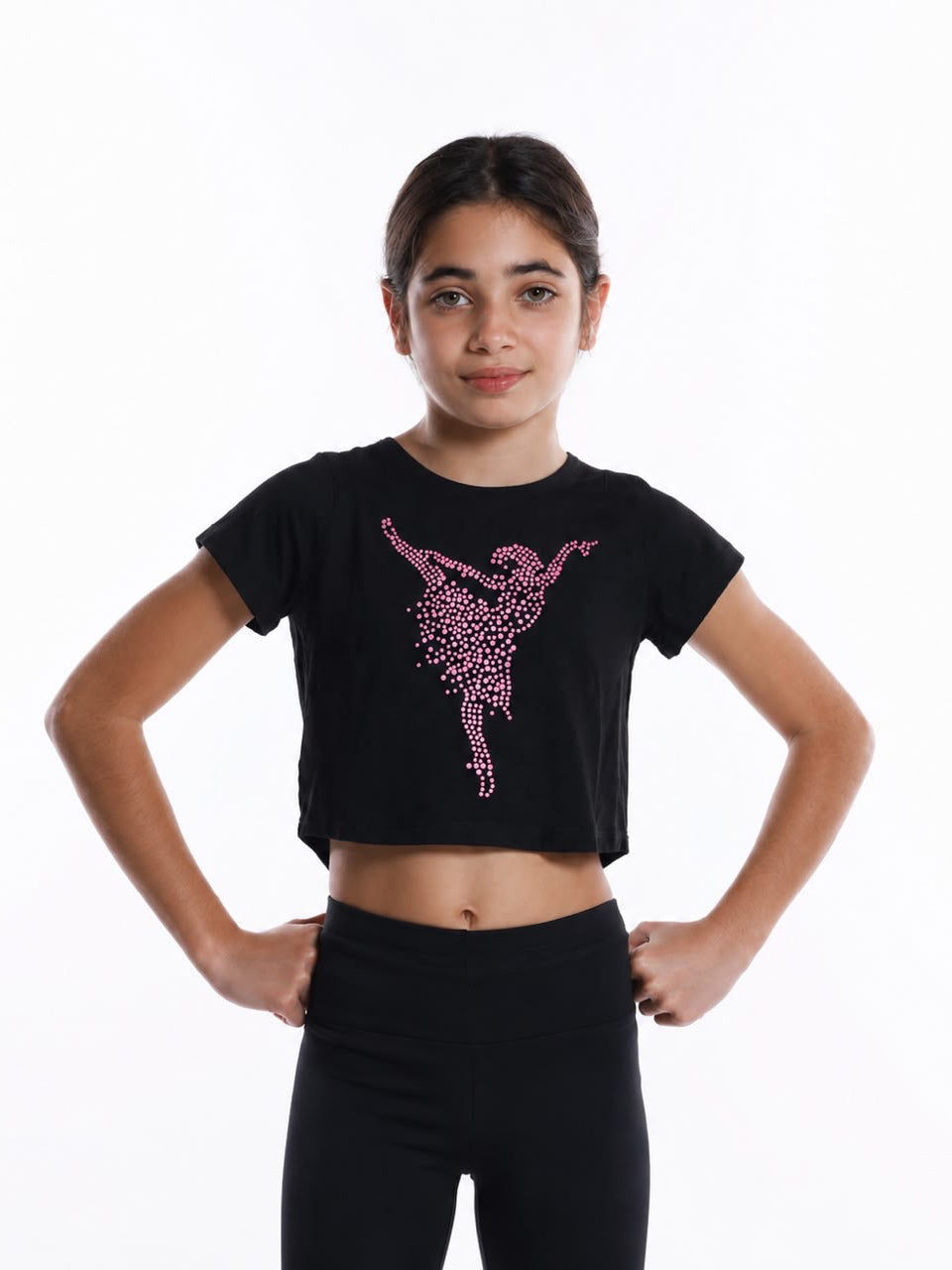 Girl wearing a black half-sleeve dance crop top featuring a pink rhinestone ballerina design, paired with black leggings for dance practice.