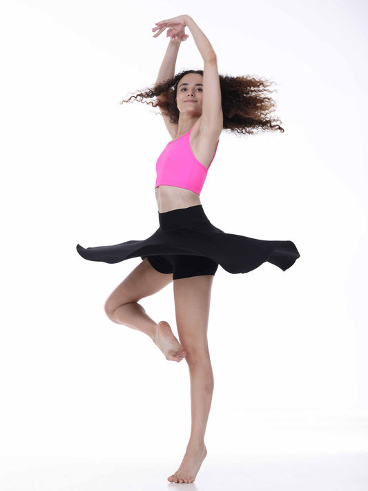Dancer in a pink top and black skirt on a white background