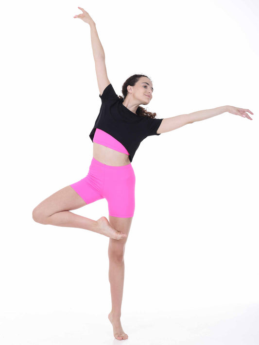 Dancer in black top and pink shorts posing on a white background