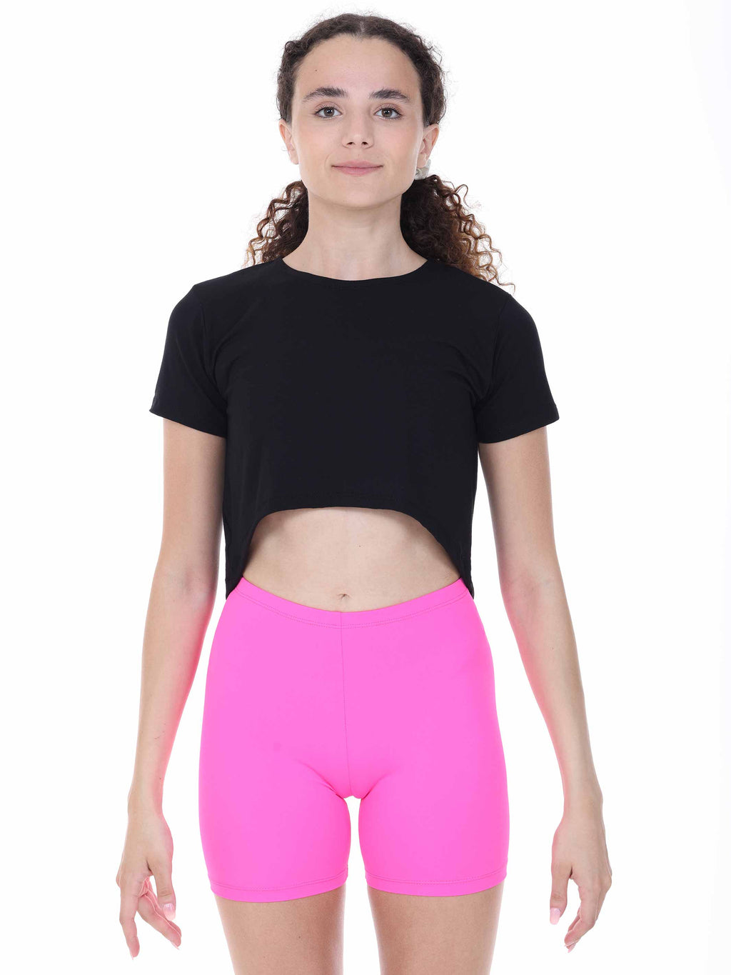 Person wearing a black dance crop top and pink shorts on a white background
