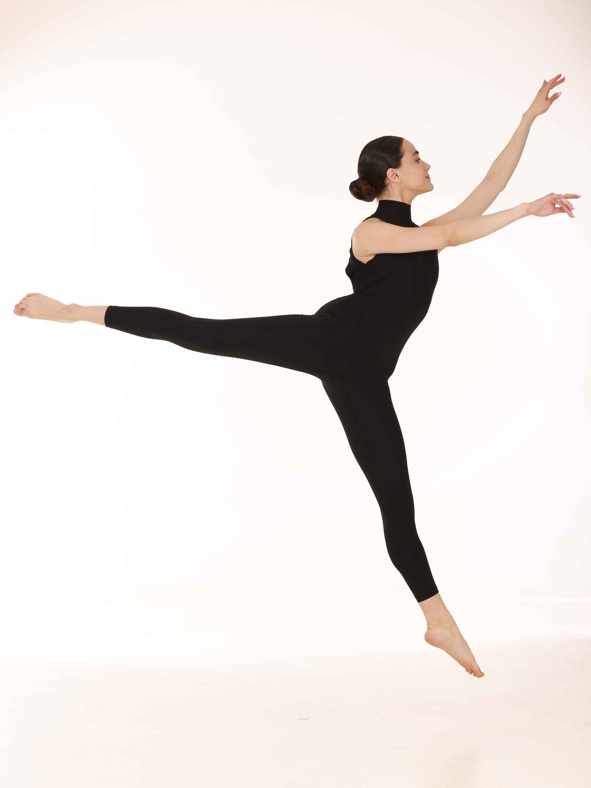 Dancer in a black unitard performing a pose on a white background