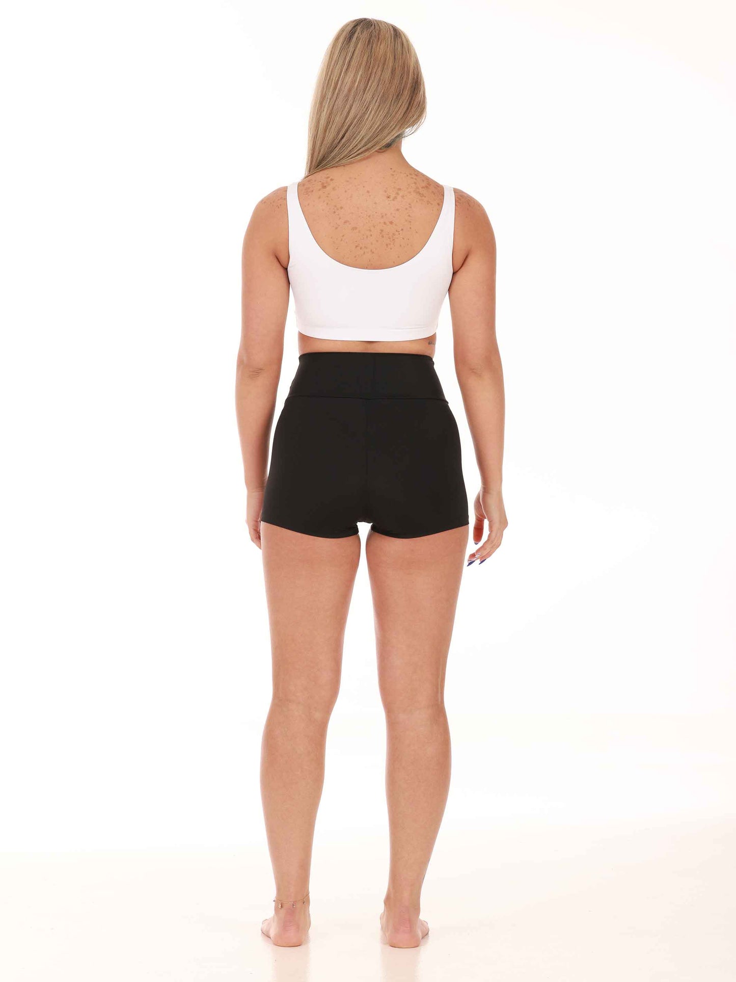 Person wearing a white tank top and black high-waisted shorts on a white background