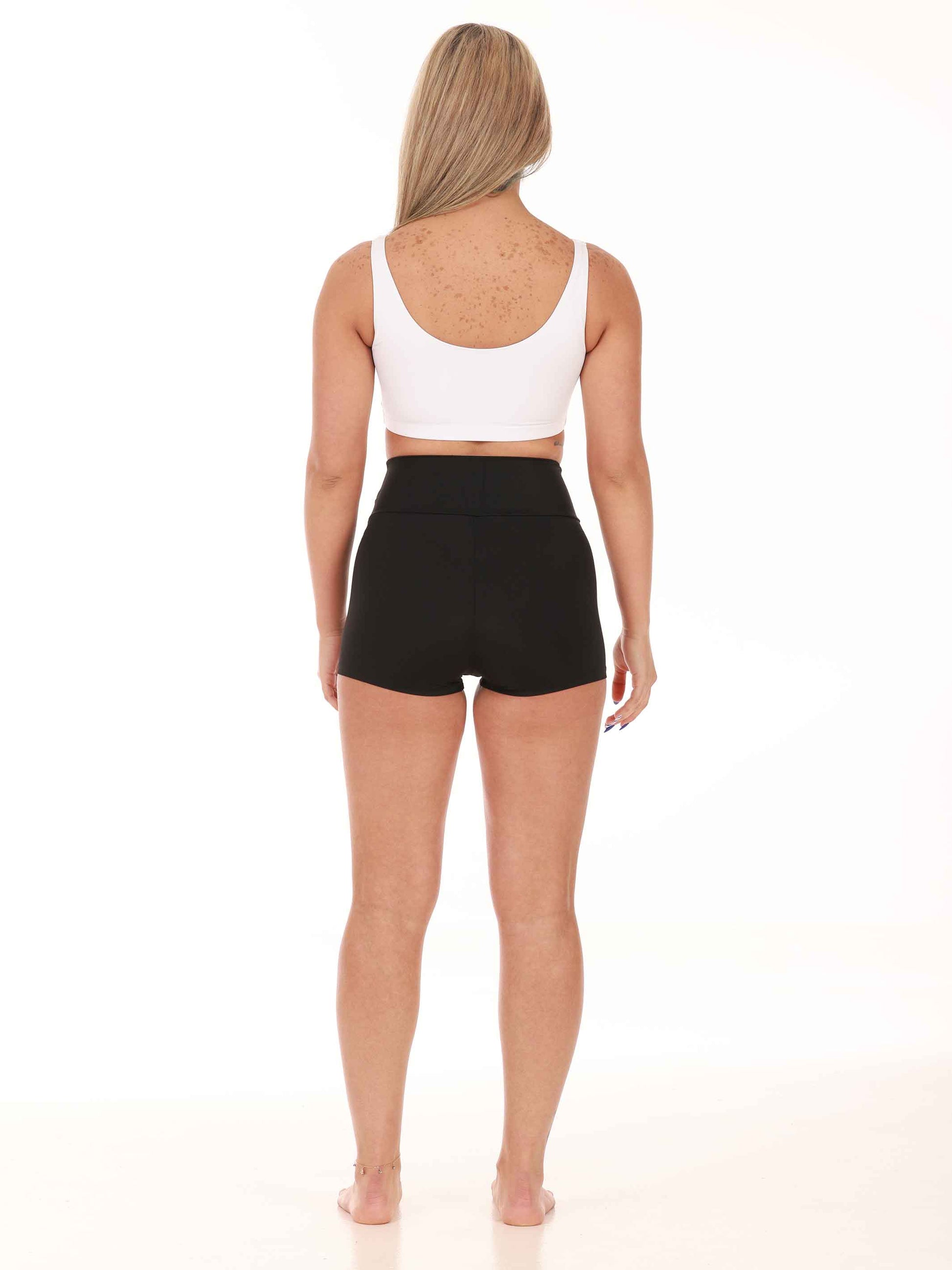 Person wearing a white tank top and black high-waisted shorts on a white background