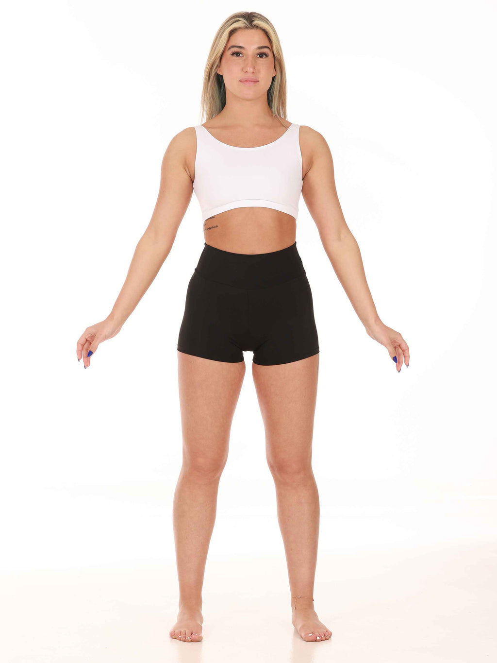 Woman wearing a white sports bra and black shorts on a white background