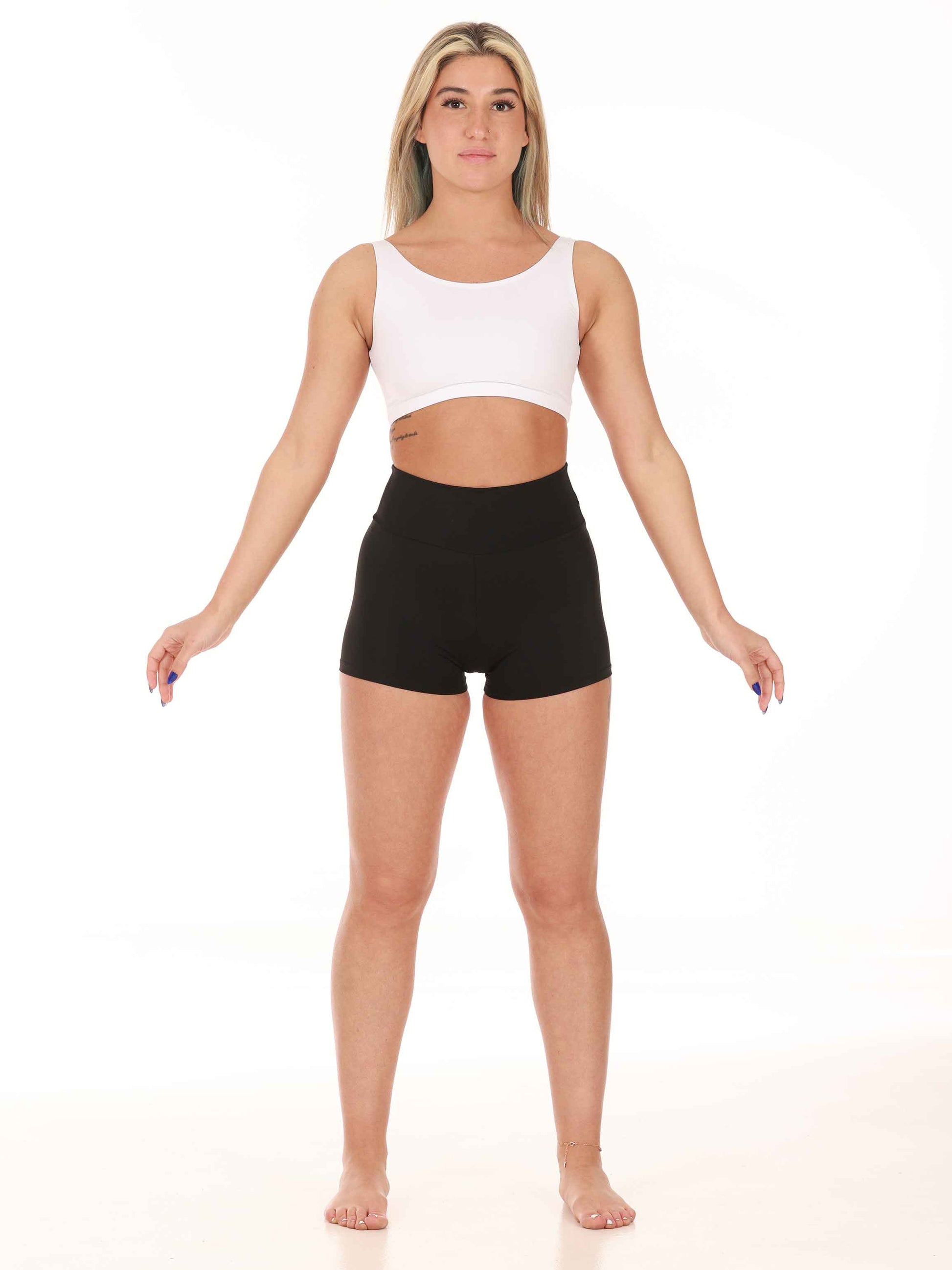 Woman wearing a white sports bra and black shorts on a white background