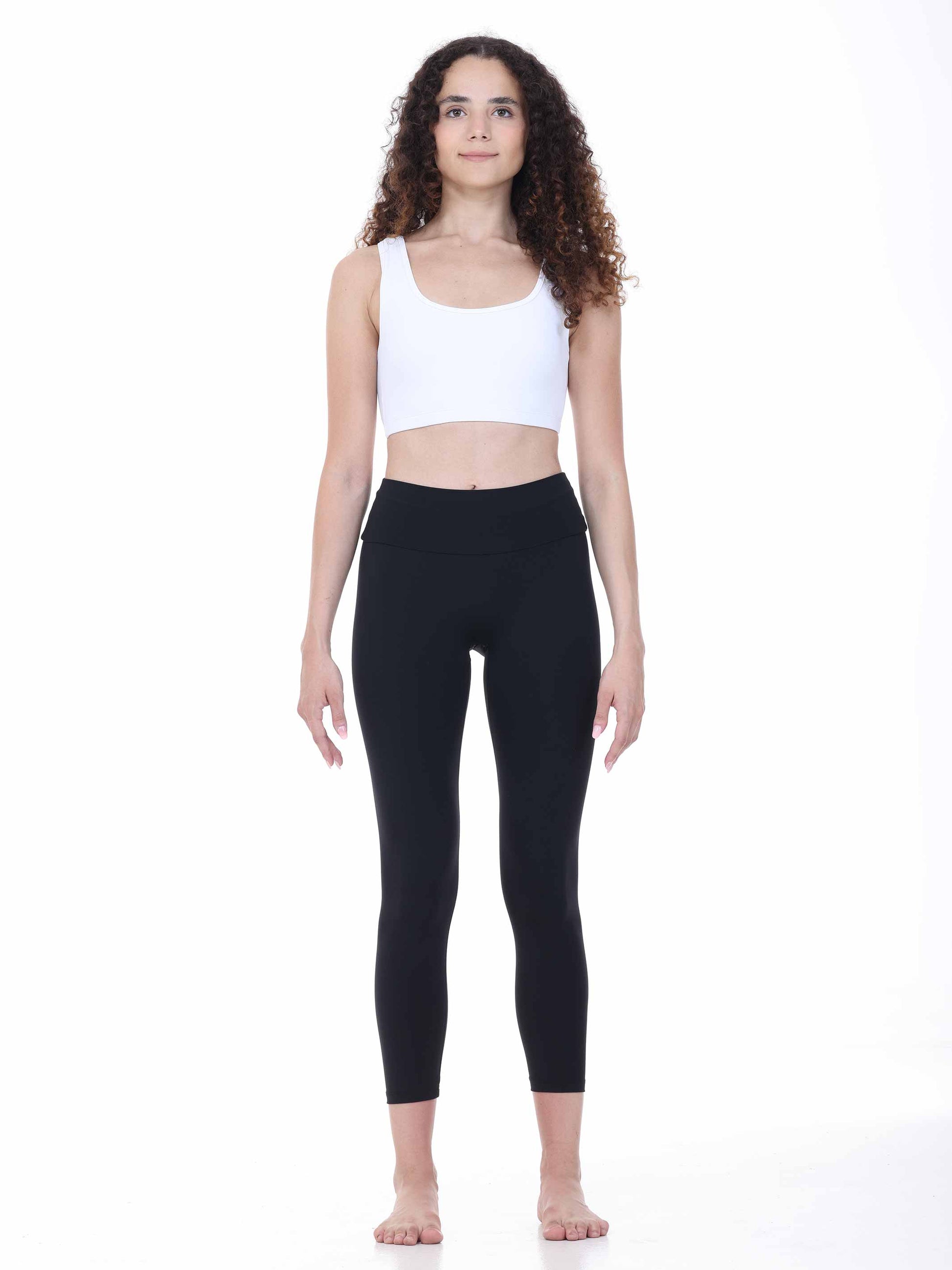 Woman wearing a white tank top and black leggings on a white background