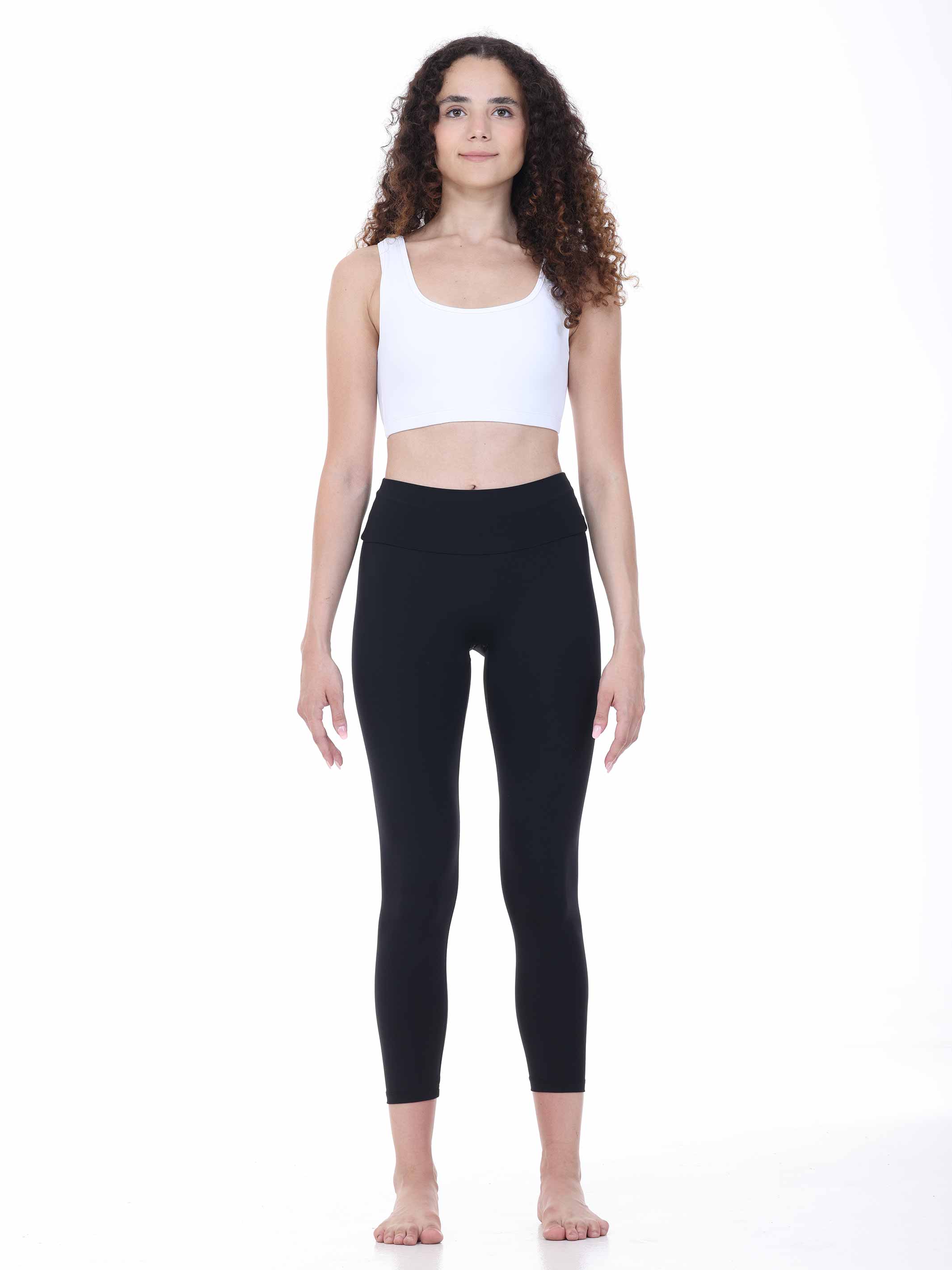 Woman wearing a white tank top and black leggings on a white background