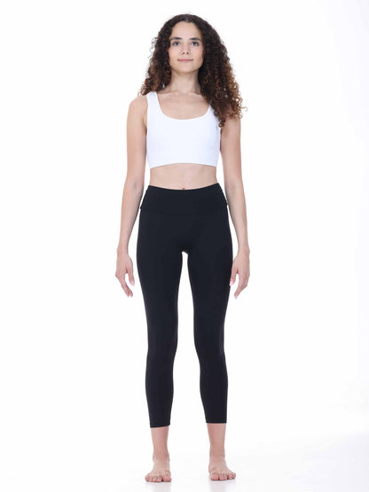 Woman wearing a white tank top and black leggings on a white background