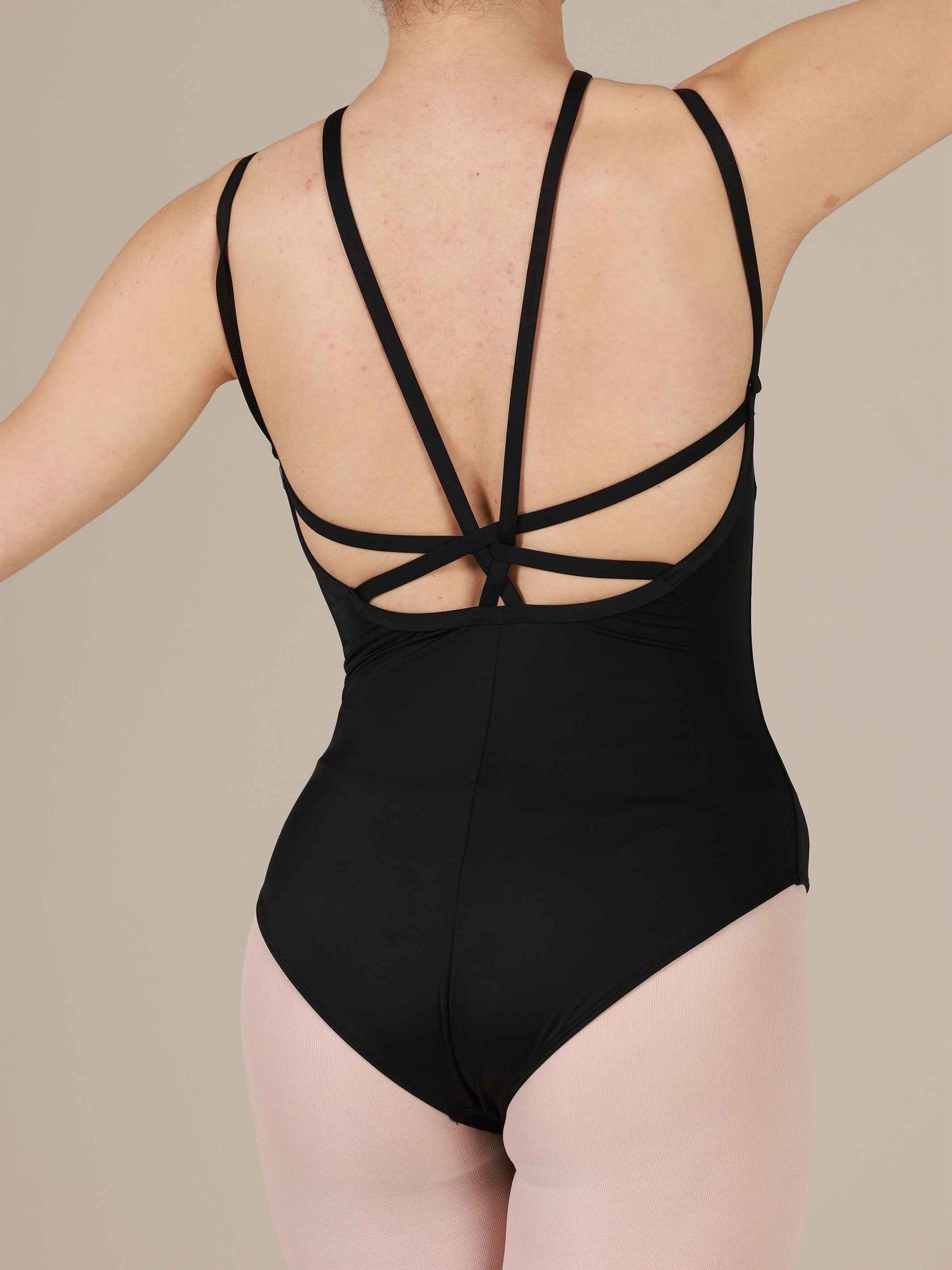 Black leotard with criss-cross straps on a neutral background