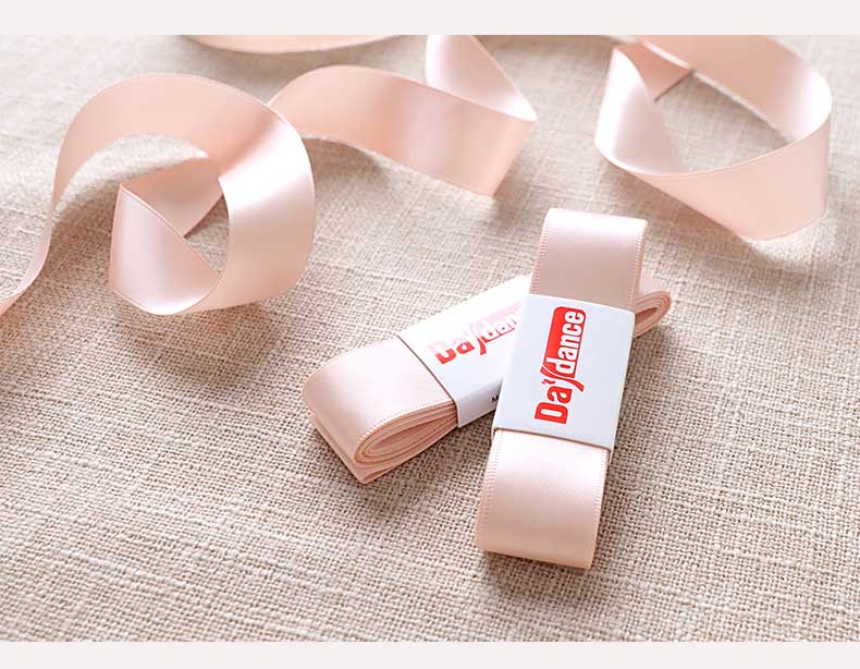 Pink ribbons with a brand label on a textured beige surface