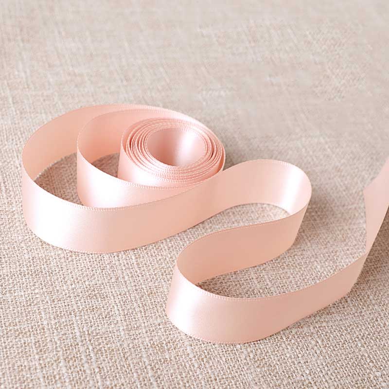 Pink satin ribbon on a textured beige background