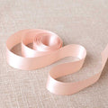 Pink satin ribbon on a textured beige background