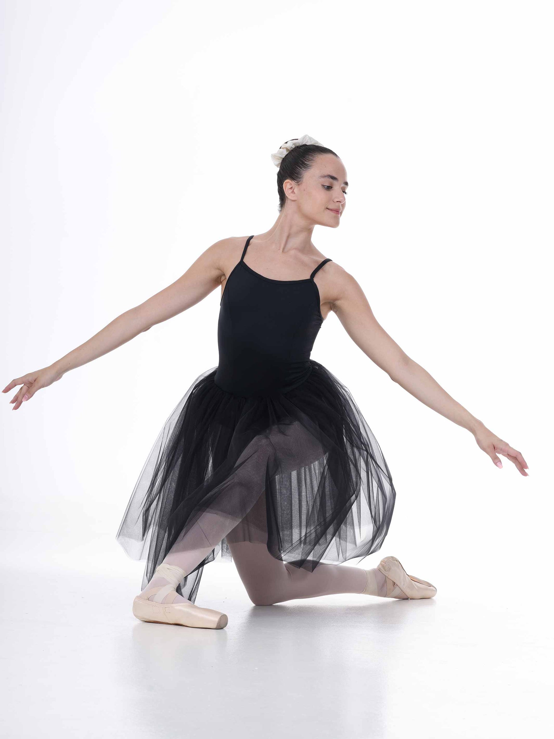 Ballerina in a black tutu dress posing on a white background