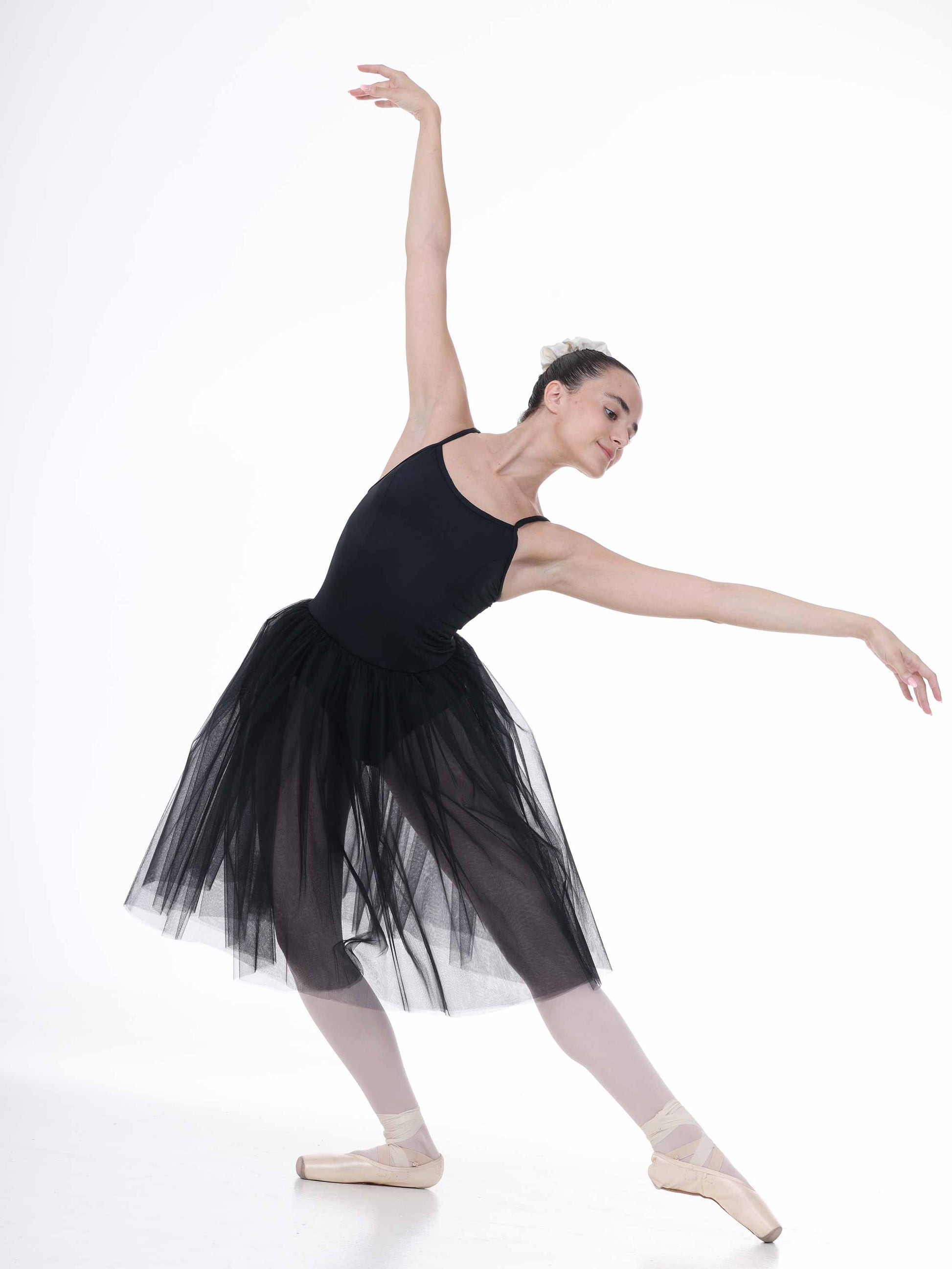 Ballerina in a black tutu posing on a white background