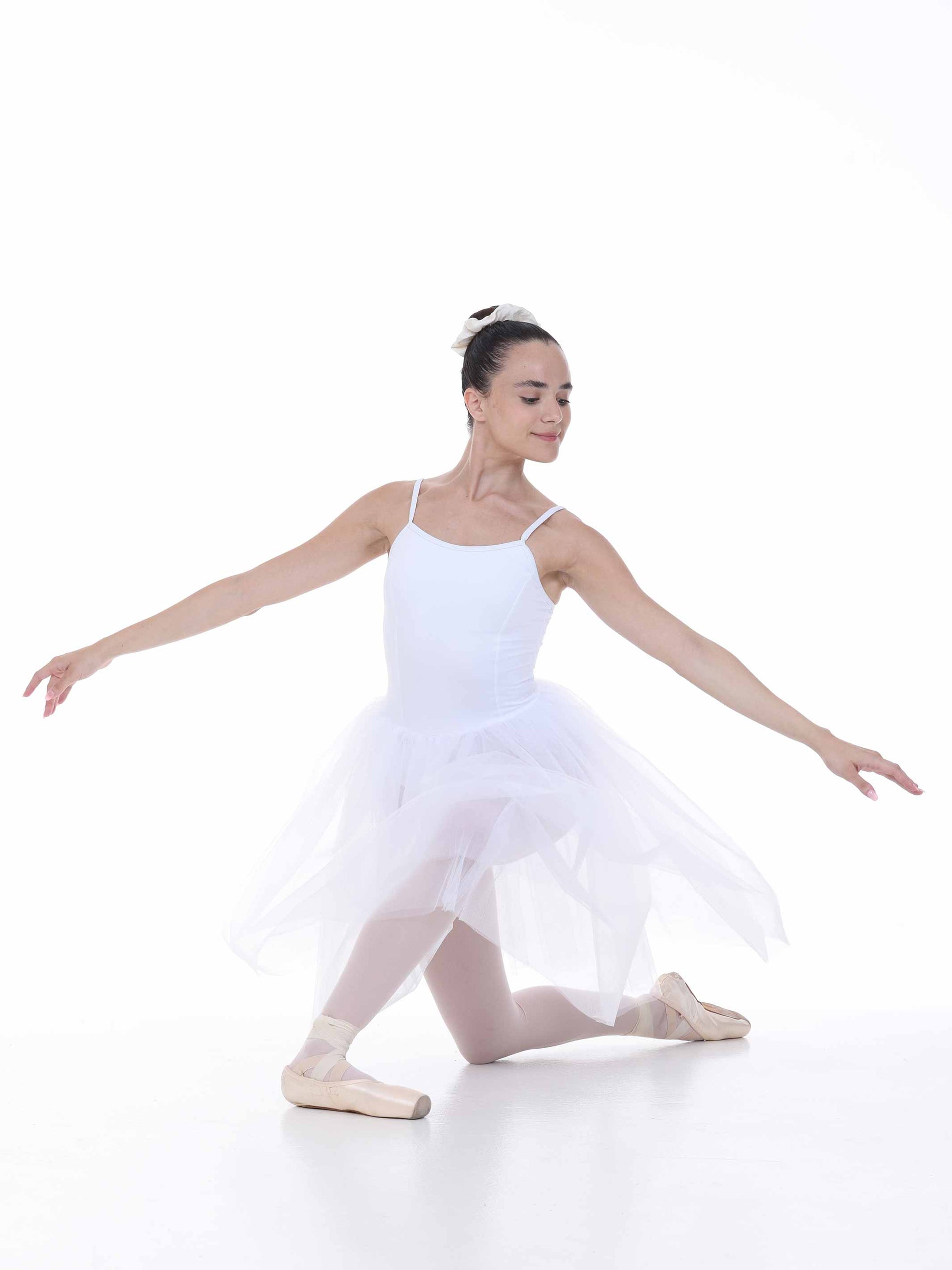 Ballerina in a white tutu posing on a white background