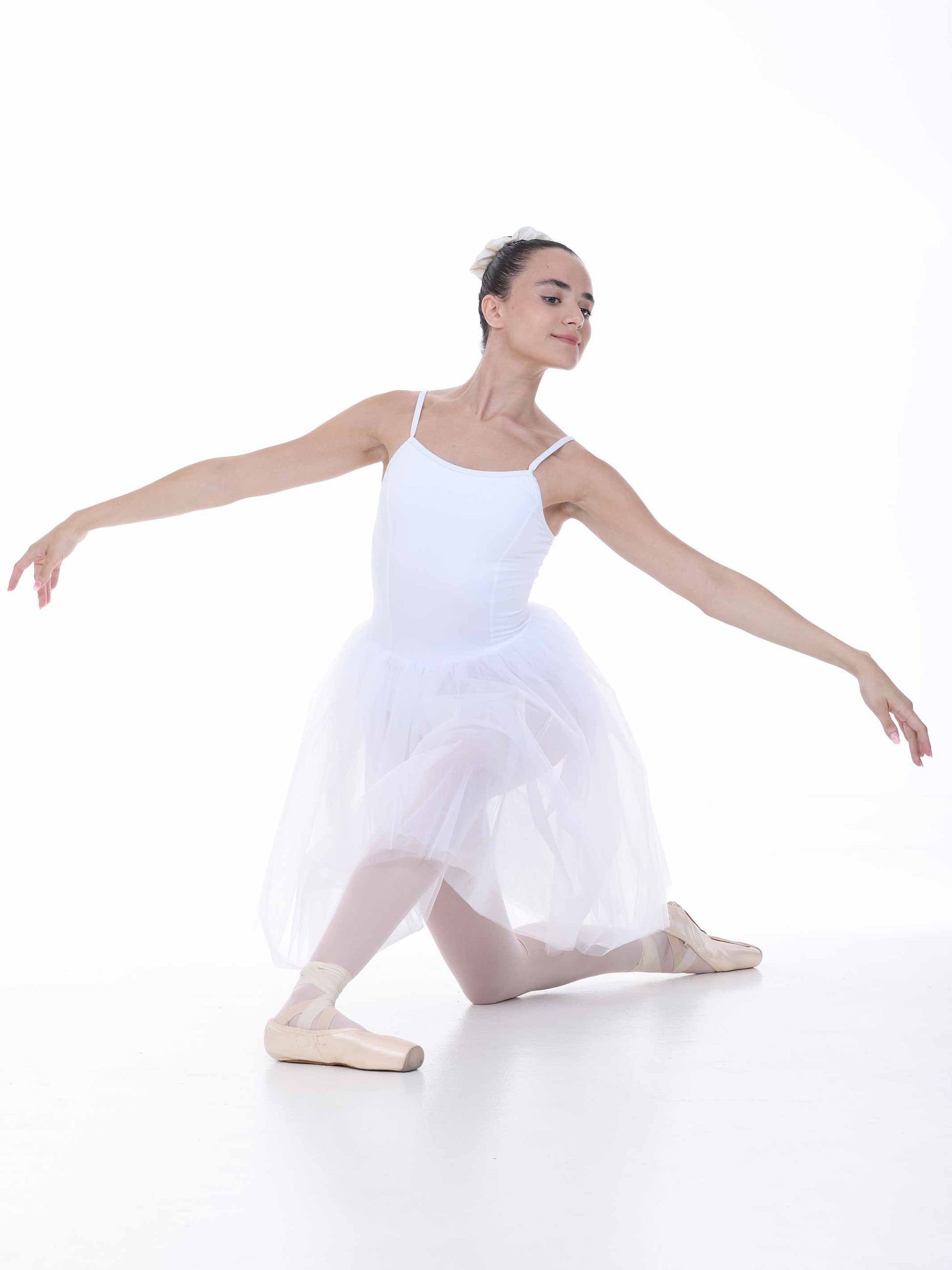 Ballerina in a white tutu dress and tights posing on a white background