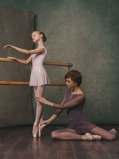 Two ballet dancers in a studio setting with a greenish-brown background.