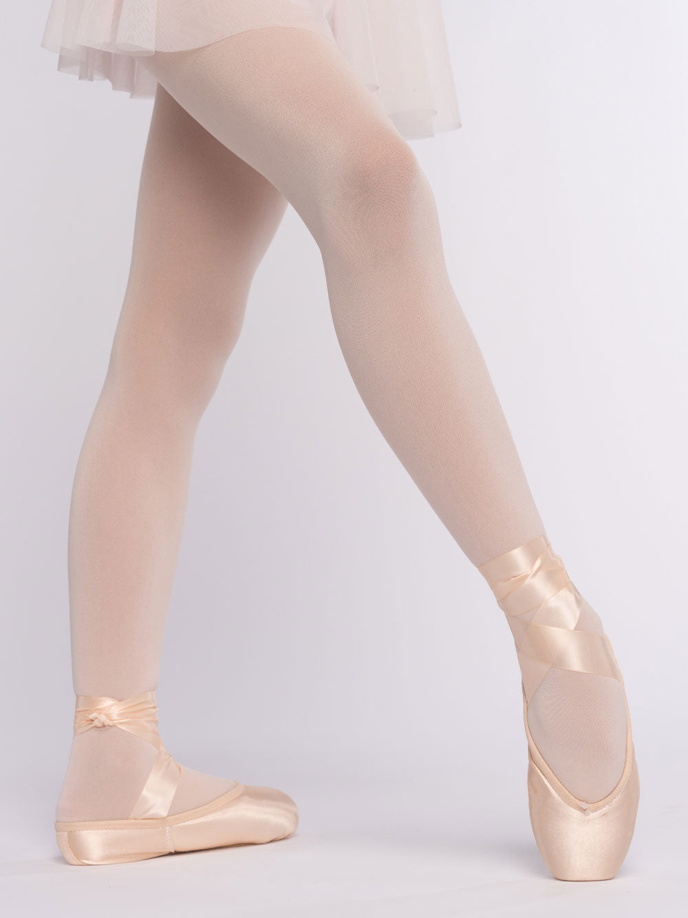 Ballerina wearing pointe shoes and a tutu on a plain background