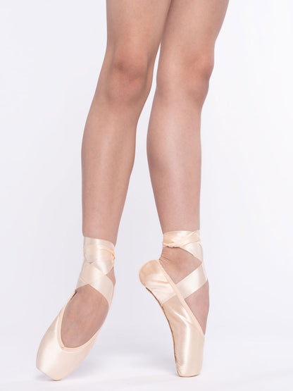 Ballet dancer wearing pointe shoes on a plain background