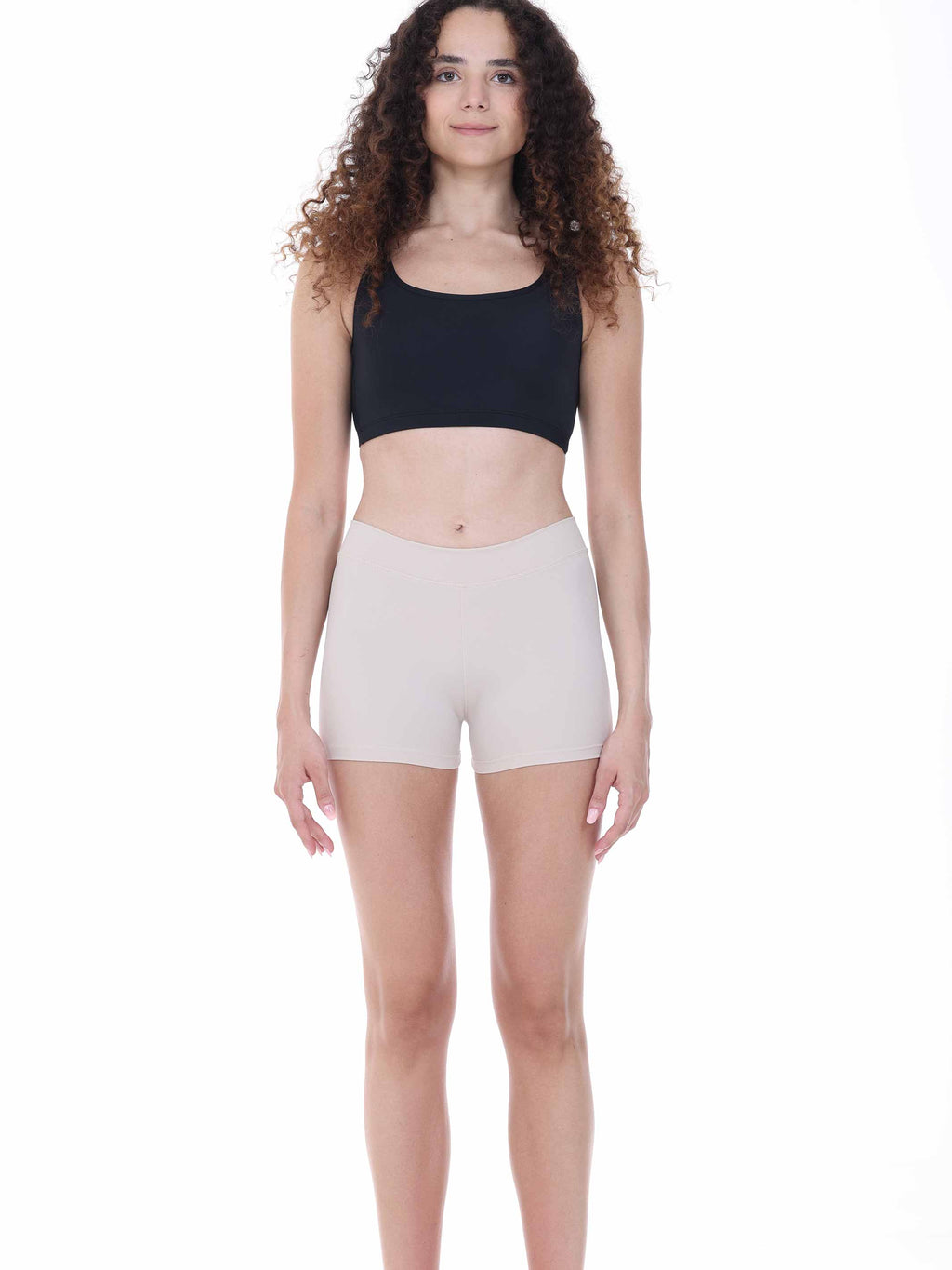 Woman wearing a black crop top and beige shorts on a white background