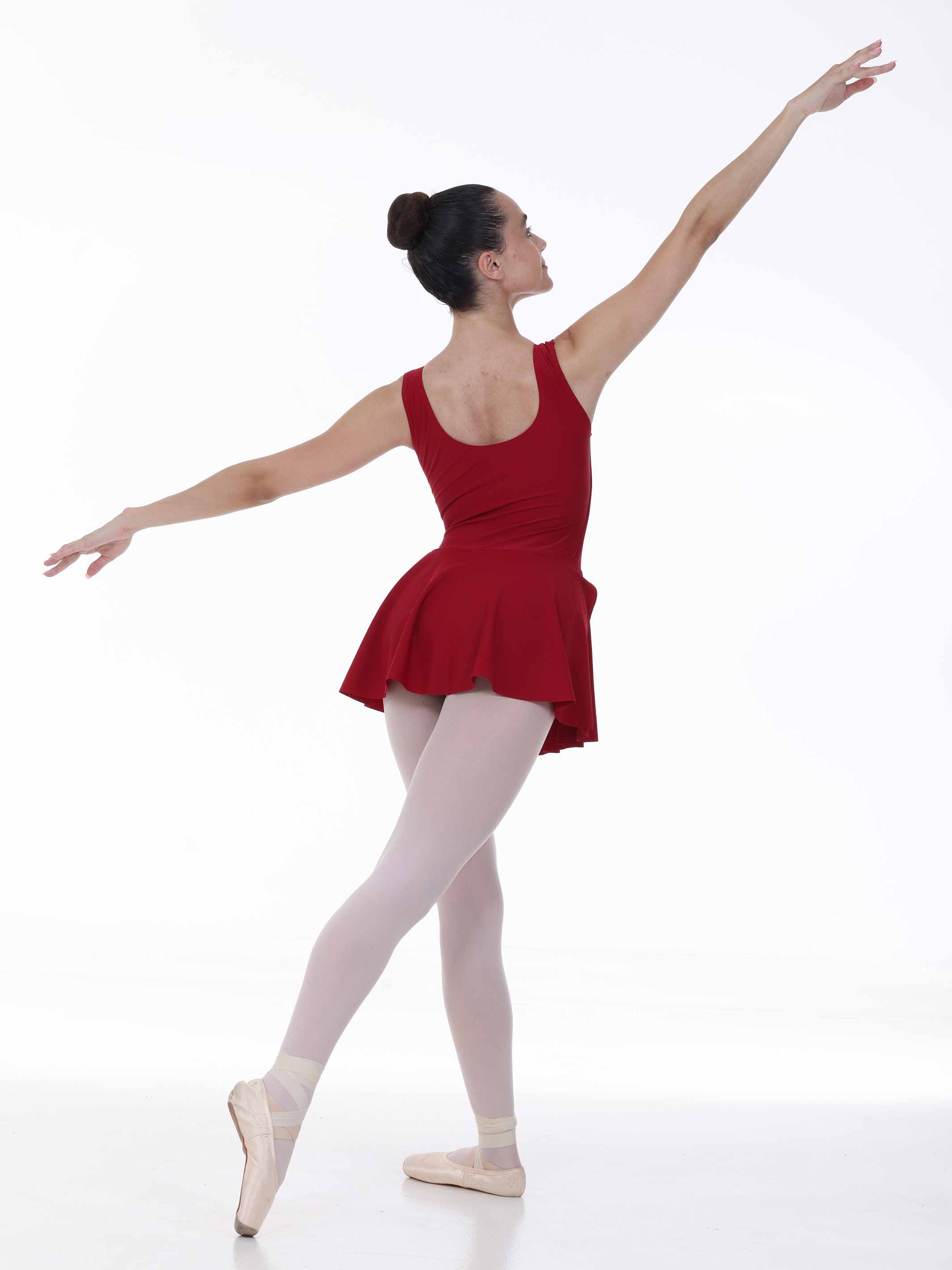 Ballerina in a red dress and white tights posing on a white background