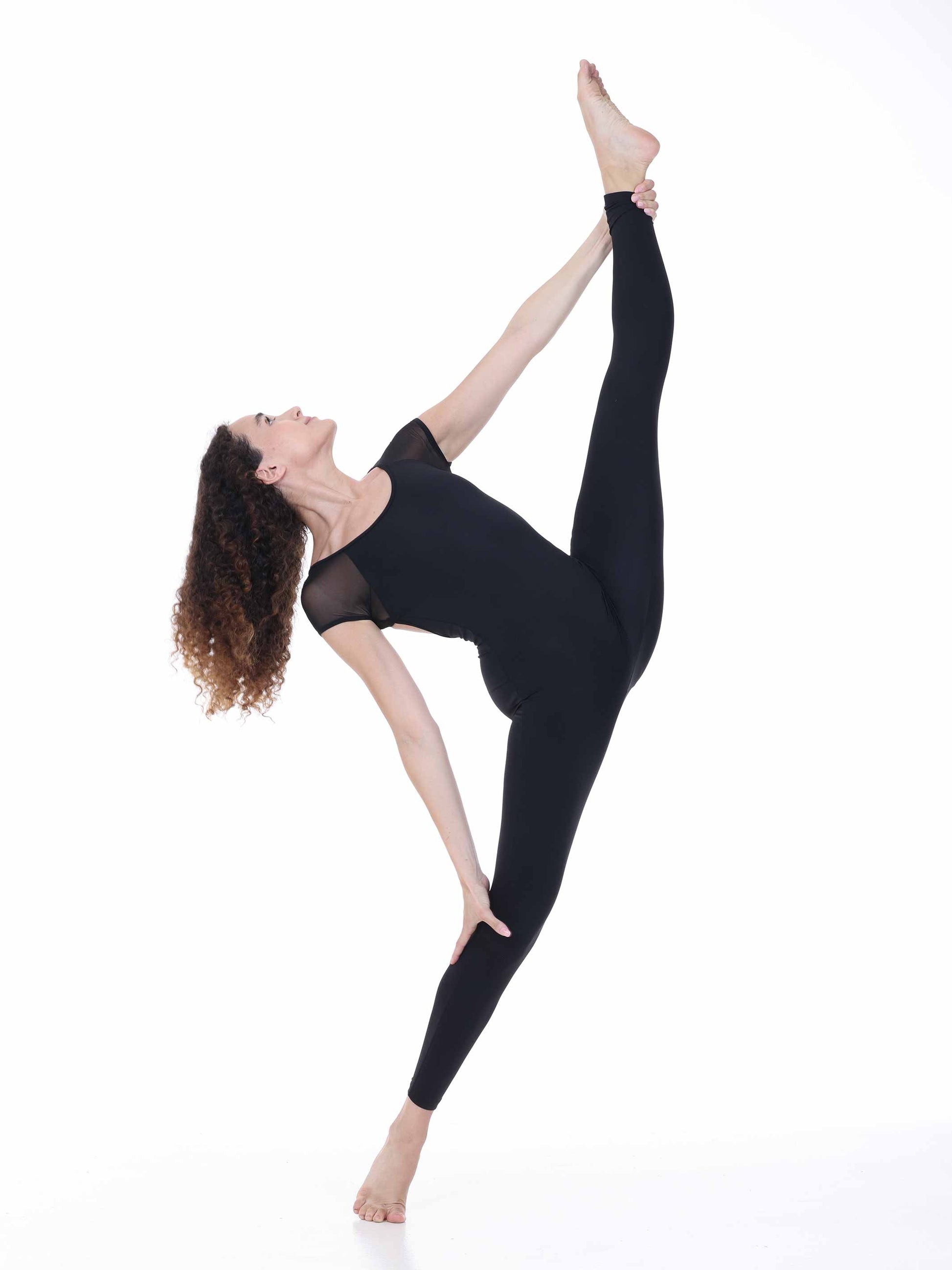 Woman in black athletic wear performing a yoga pose on a white background