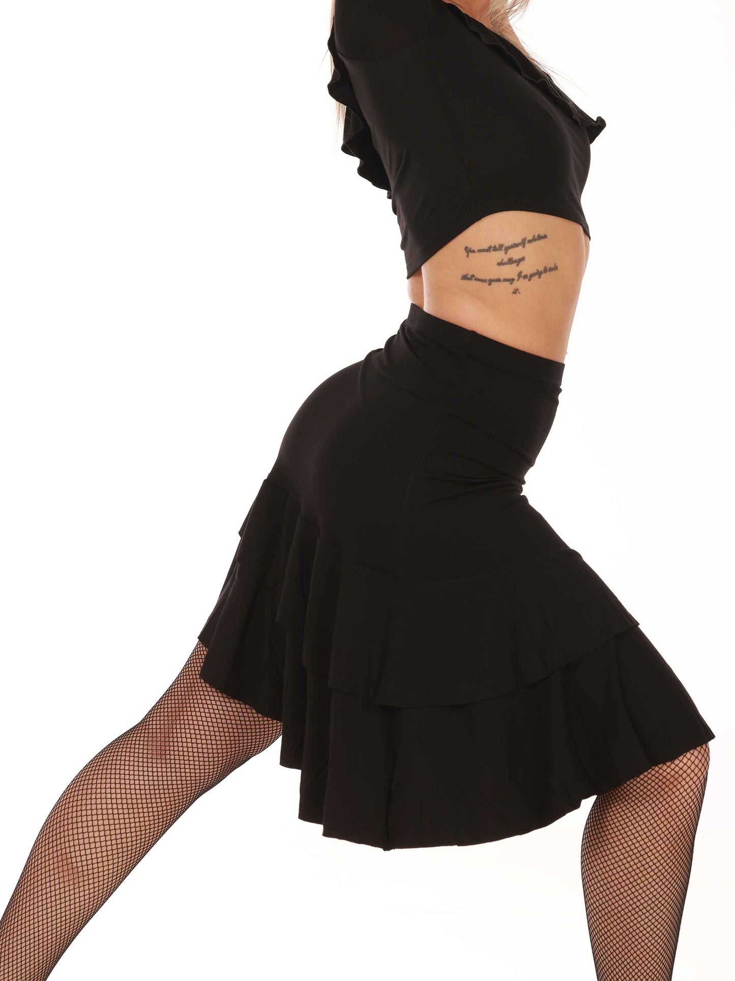 Person wearing a black dance skirt with ruffled layers on a white background
