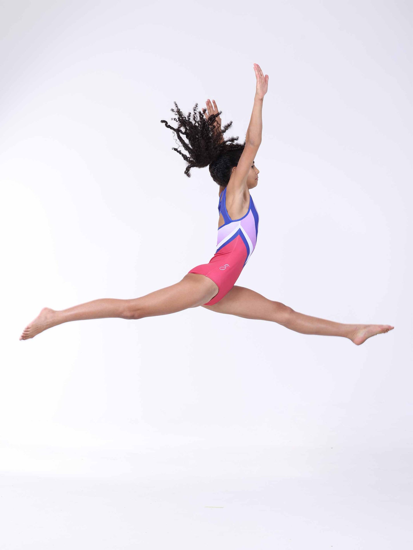 Gymnast in a pink and blue gymnastics leotard performing a jump on a white background